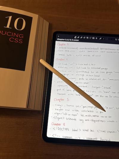 CSS textbook open next to an ipad with notes